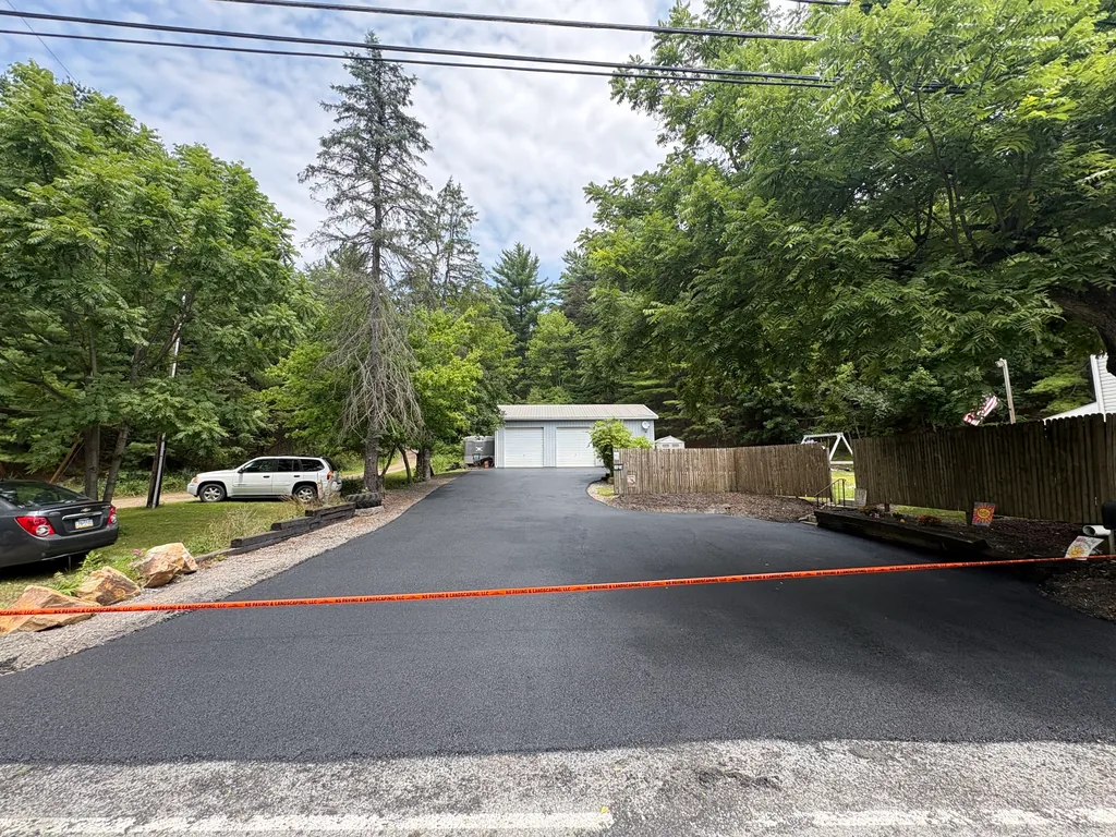 Freshly paved asphalt driveway taped off in front of a detached two car garage, asphalt driveway paving