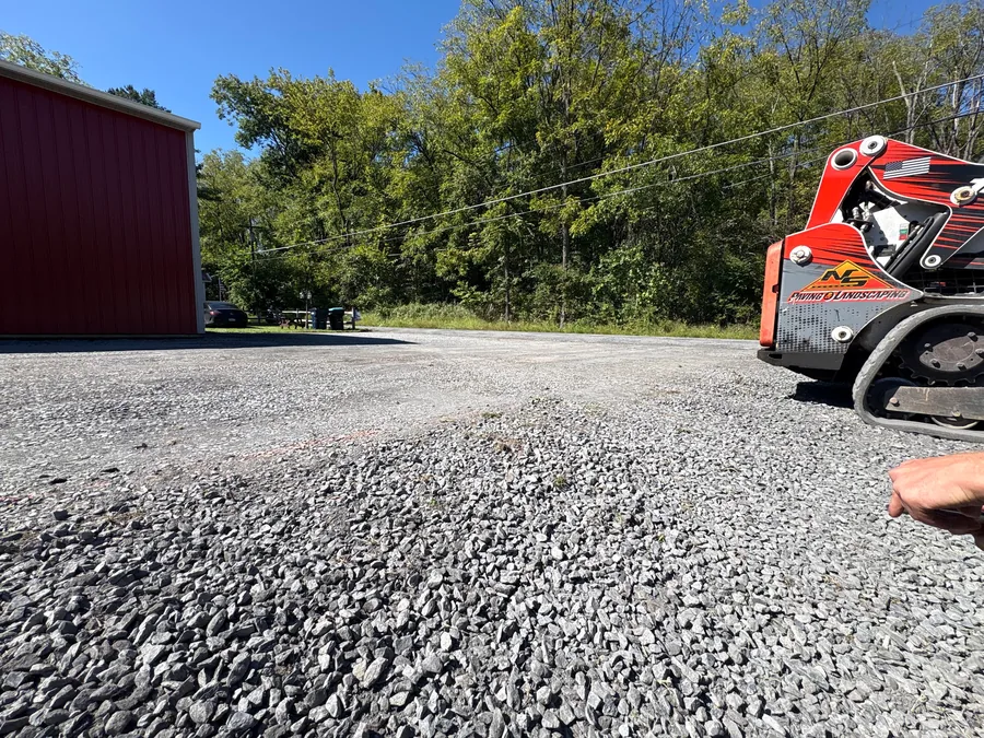 Freshly graded crushed stone driveway beside a compact track loader, gravel driveway regrading