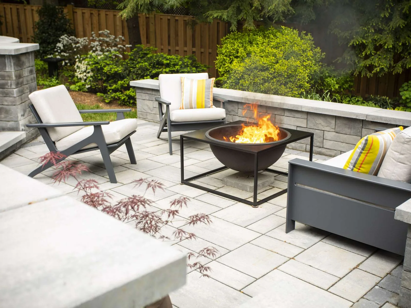 Gray paver patio with block seat walls and a fire bowl inside a privacy fence, hardscaping and patios