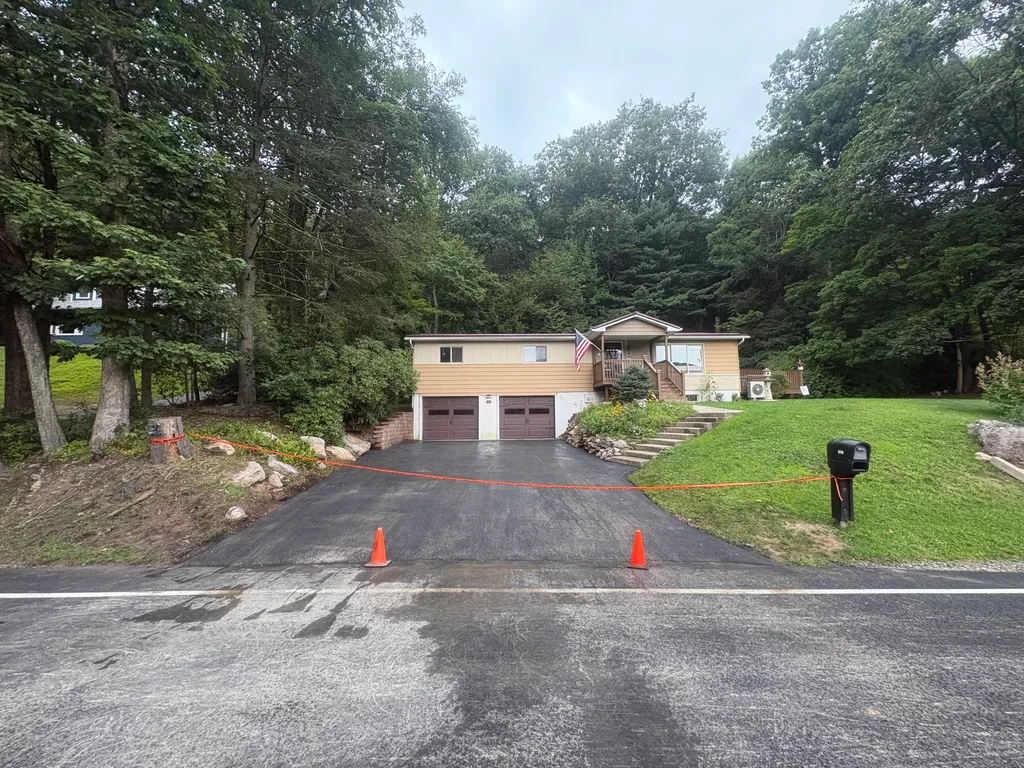 Planted flower bed and stone steps on a sloped front lawn beside a driveway, landscape design