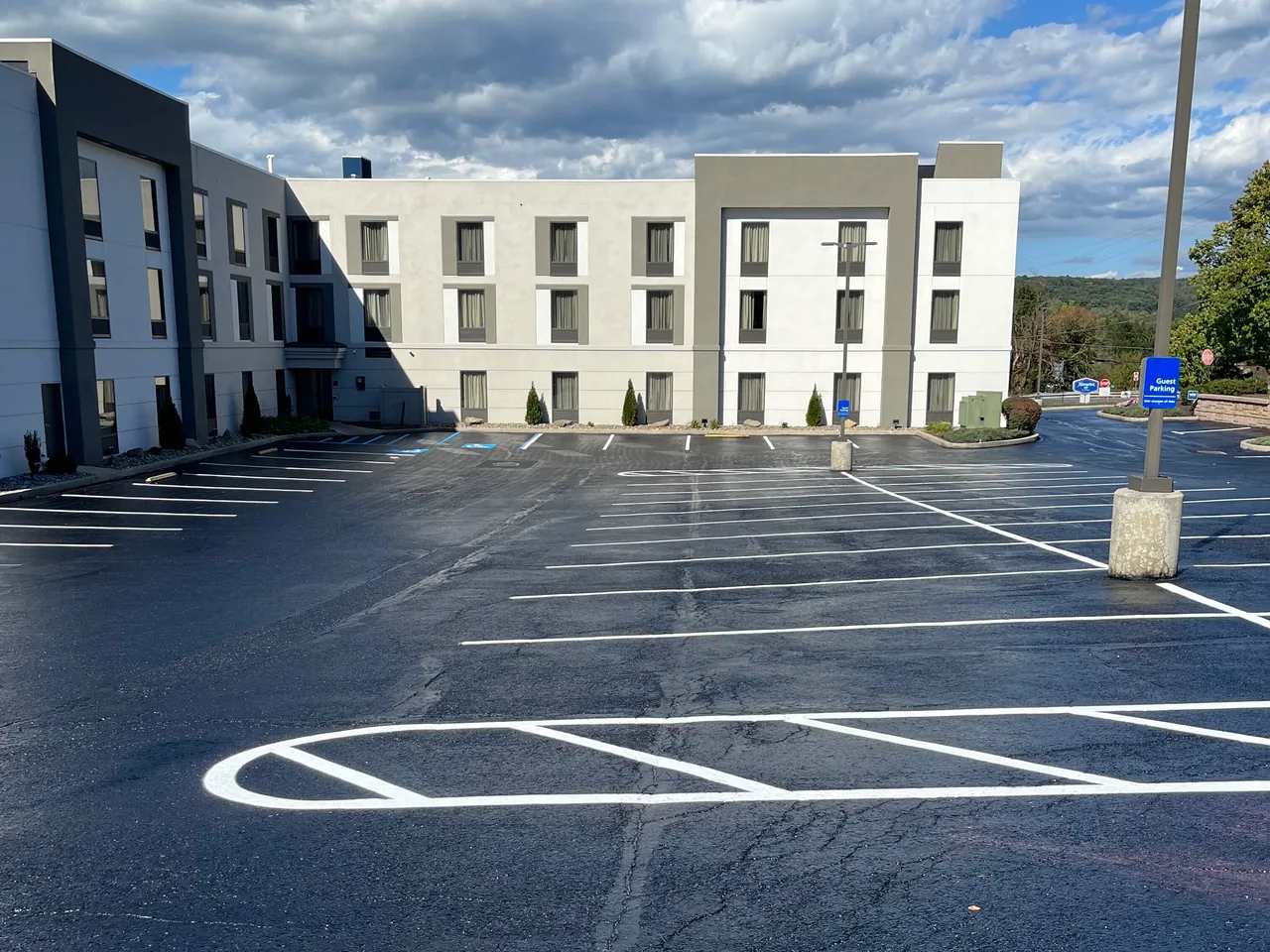 Commercial parking lot with a fresh black surface and new white stall lines, parking lot paving